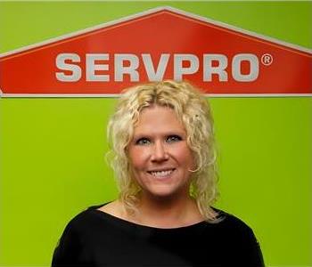 Female with black shirt with Green wall and SERVPRO logo in the Background 