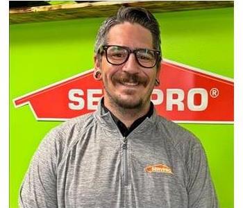 Man in Grey Shirt in Front of a Green Background 