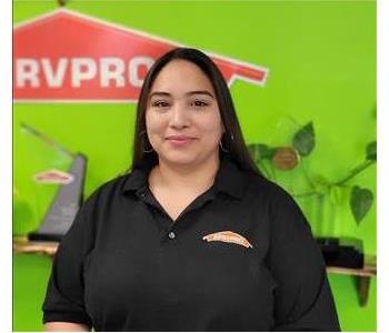 Female with black shirt with Green wall and SERVPRO logo in the Background 