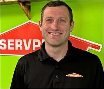 Man with black shirt with Green wall and SERVPRO logo in the Background 