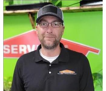 Man with black shirt with Green wall and SERVPRO logo in the Background 