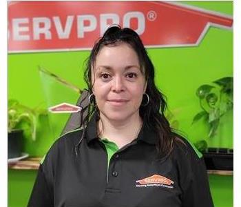 Female with black shirt with Green wall and SERVPRO logo in the Background 