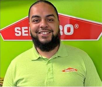 Man with green shirt with Green wall and SERVPRO logo in the Background 