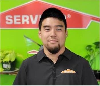 Man with black shirt with Green wall and SERVPRO logo in the Background 