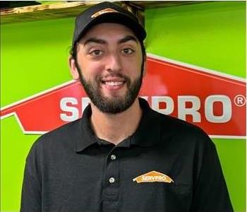 Man with black shirt with Green wall and SERVPRO logo in the Background 