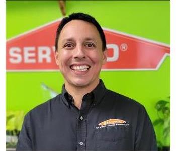 Man with black shirt with Green wall and SERVPRO logo in the Background 