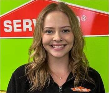 Female with black shirt with Green wall and SERVPRO logo in the Background 