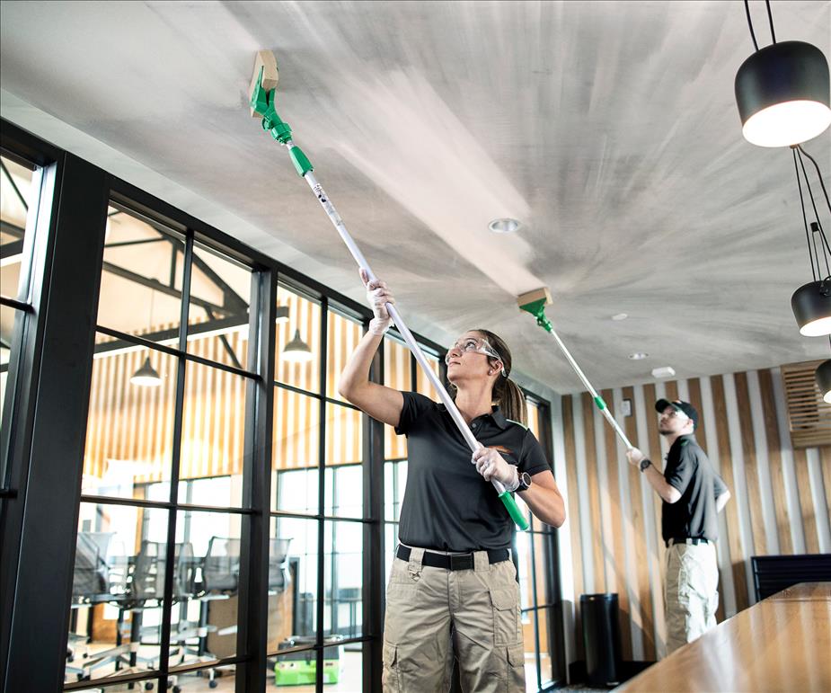 Two SERVPRO workers cleaning soot off a ceiling due to fire.